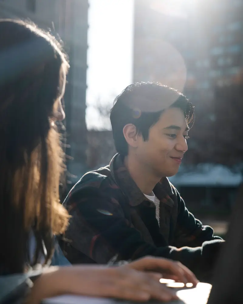 Dos jóvenes conversan mientras estudian con una computadora portátil